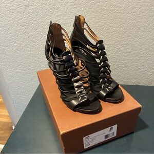 Coach Josey black leather gladiator high heels with a snake print design.